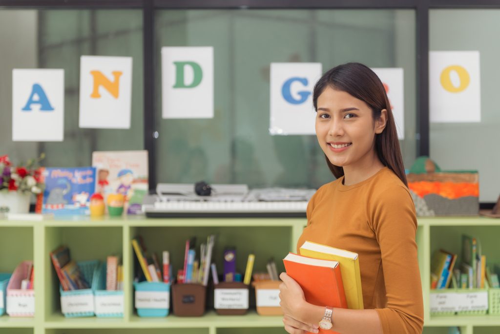 pretty asian teacher smiling camera back classroom elementary school vintage effect style pictures
